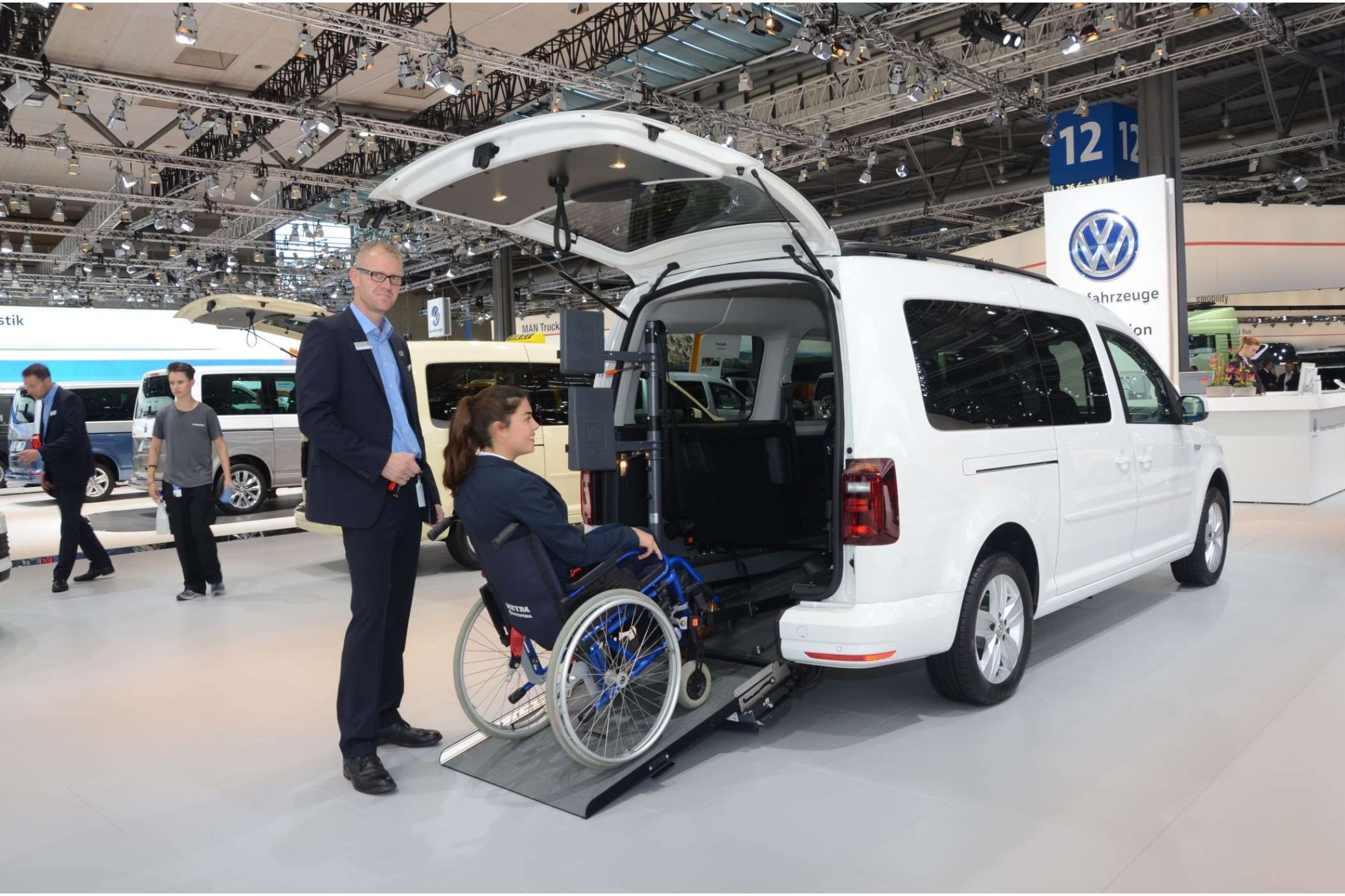 Stefan Geveke, Verkäufer bei AMF-Bruns, zeigte mit Unterstützung einer Hostess das neue elektrische Rollstuhl-Einzugssystem „Easy Pull“. Es soll zarten Taxifahrerinnen dabei helfen, auch schwere Fahrgäste in E-Rollis über eine stärker geneigte Rampe einzuladen. Das soll eine Heckabsenkung zur Abflachung der Rampe erübrigen.| Foto: Dietmar Fund