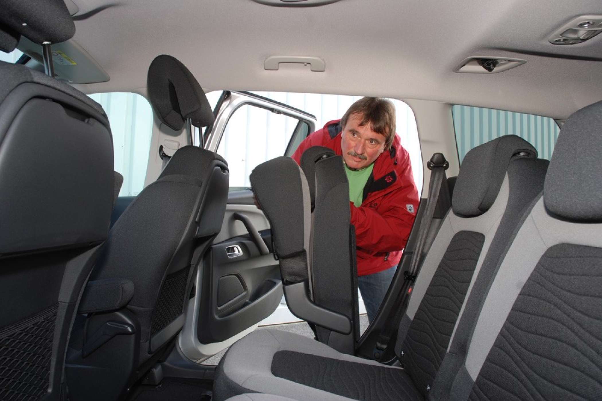 Wenn man am Griff oben an der Lehne des Sitzes an der Schiebetür zieht, klappt dessen Sitzfläche nach oben und man kann ihn nach vorn schieben, um den Durchstieg frei zu machen.| taxi-heute | Dietmar Fund