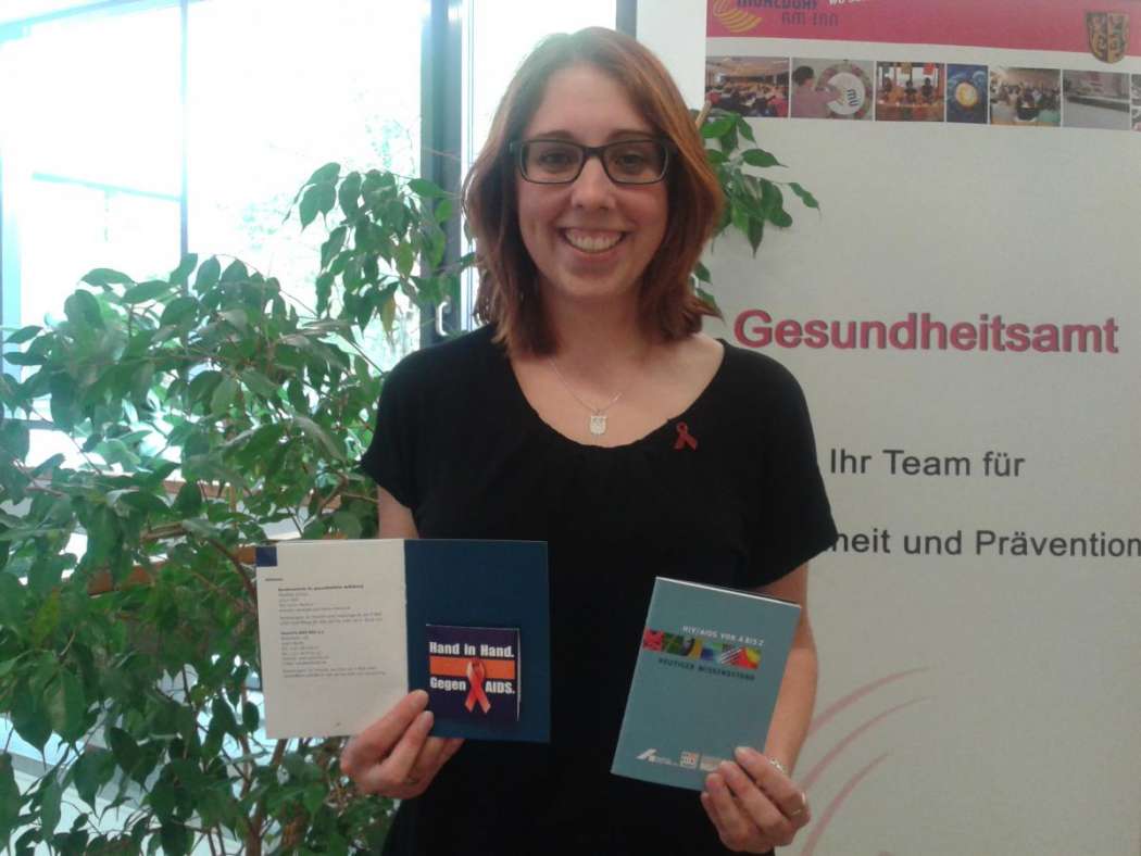 Die Sozialpädagogin Anna Fischer vom Mühldorfer Gesundheitsamt zeigt die Infobroschüre samt Kondom, die die Taxifahrer während eines Volksfestes verteilen. (Foto: Landratsamt Mühldorf a. Inn)