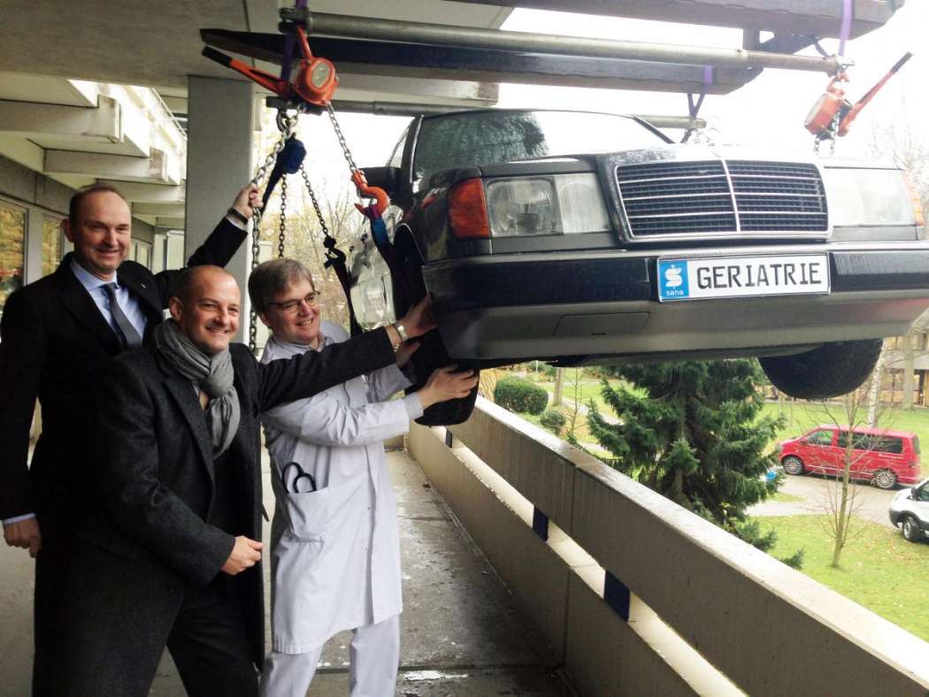 Am Kran empfangen Klinik-Geschäftsführer Dr. Stephan Puke (v.l.), Niederlassungsleiter Lars Reuter und Chefarzt Dr. Wolfrid Schröer den neuen „Trainings-Mercedes“. (Foto:Sana Kliniken Duisburg)
