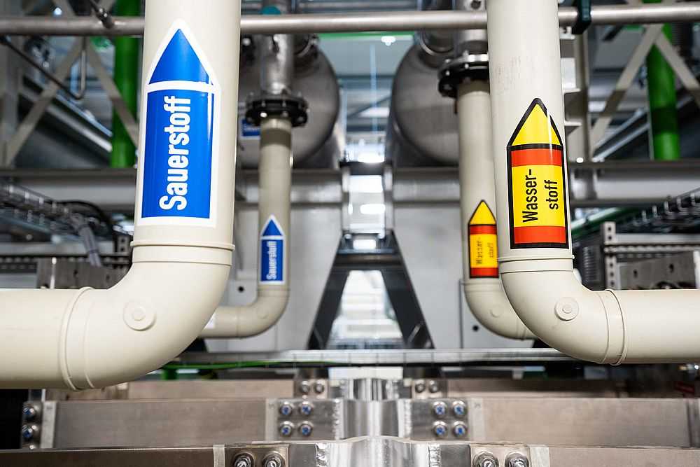 Auf Rohren einer Wasserstofferzeugungsanlage ist ein Aufkleber mit der Aufschrift "Wasserstoff" angebracht. (Foto: Nicolas Armer/dpa)