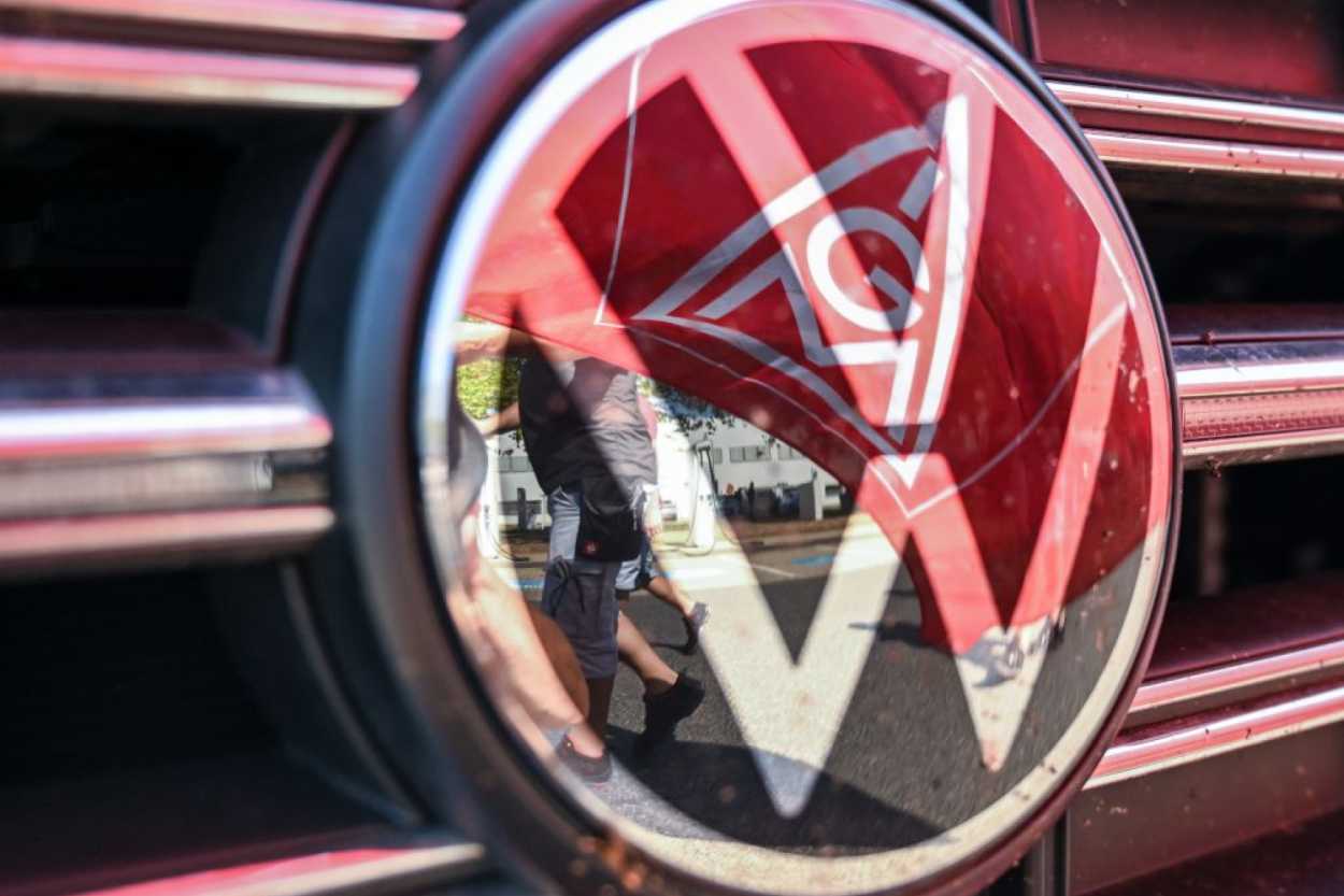 Zeichen auf Eskalation: Nach der Kündigung fast aller Tarifverträge steht VW ein heißer Herbst ins Haus. Eine Fahne der IG Metall spiegelt sich vor dem Elektro-Werk Zwickau in einem VW Logo. | Foto: dpa/Hendrik Schmidt